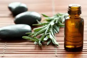 Brown bottle of Rosemary Essential Oil with sprig of rosemary.