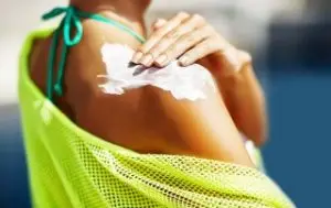 Person rubbing sunscreen into their shoulder